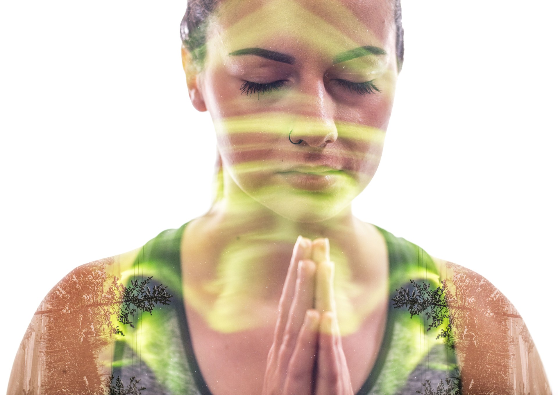 Multiple exposure of meditating woman superimposed over aurora borealis and trees